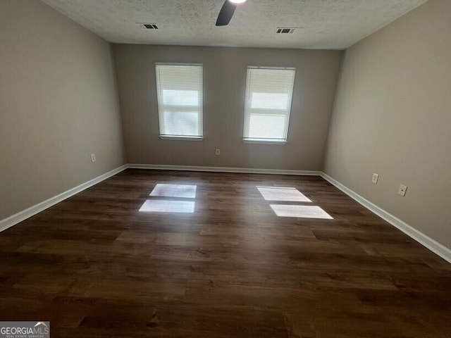 spare room featuring a textured ceiling, ceiling fan, dark wood-style floors, and baseboards