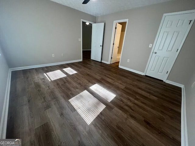 unfurnished bedroom featuring baseboards, dark wood-type flooring, and connected bathroom