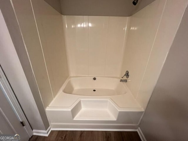 full bath with baseboards, wood finished floors, and tub / shower combination