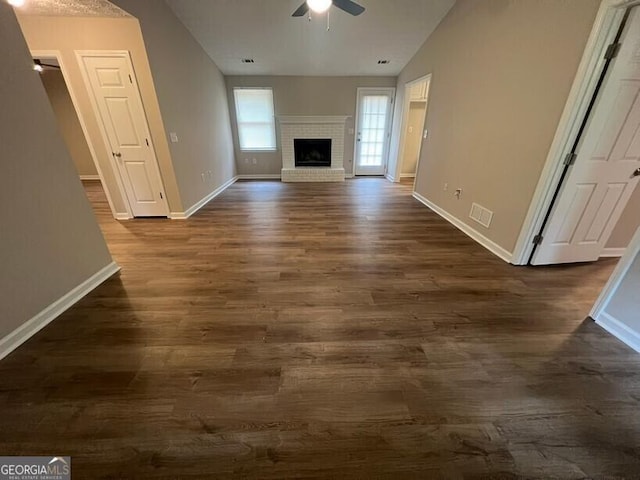 unfurnished living room featuring a ceiling fan, baseboards, and dark wood-style flooring