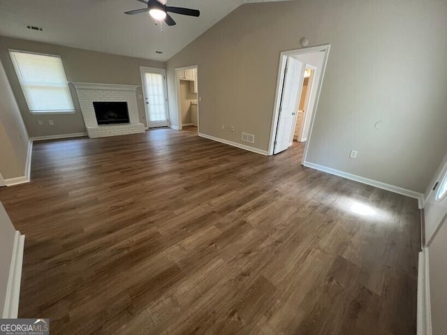 unfurnished living room with ceiling fan, vaulted ceiling, baseboards, dark wood finished floors, and a fireplace