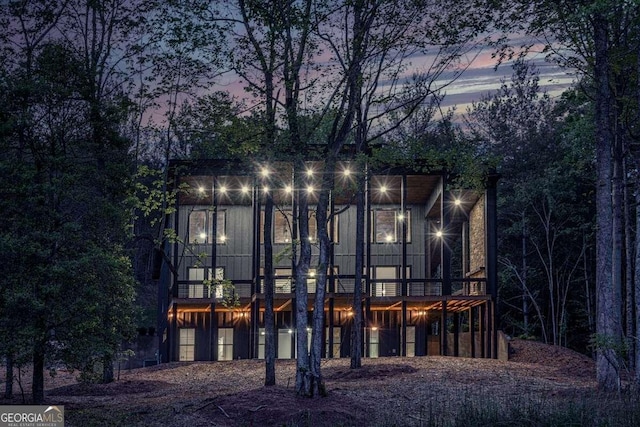 back of house at dusk with a wooden deck