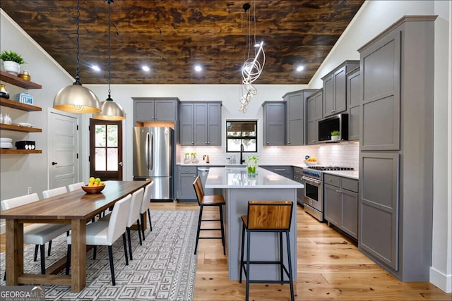 kitchen with stainless steel appliances, gray cabinetry, backsplash, open shelves, and light countertops