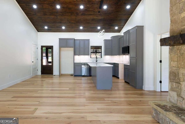 kitchen featuring gray cabinets, stainless steel dishwasher, black microwave, light wood finished floors, and a center island