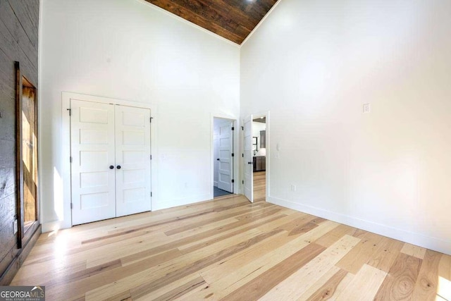 unfurnished bedroom with light wood-style flooring, high vaulted ceiling, baseboards, a closet, and wooden ceiling