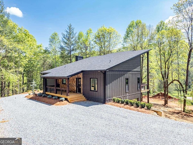 chalet / cabin featuring board and batten siding, a shingled roof, and gravel driveway