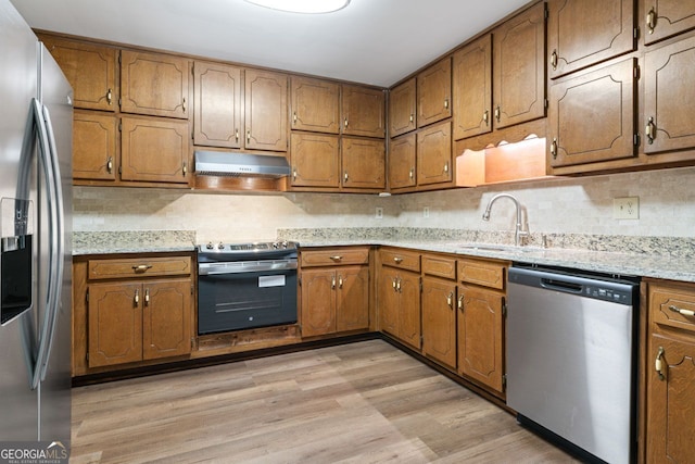 368 Henry Higgins Rd, Jackson, GA 30233 - kitchen with stainless steel appliances, under cabinet range hood, a sink, light wood-style floors, and brown cabinets