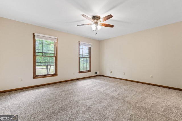 spare room featuring a ceiling fan, light carpet, and baseboards