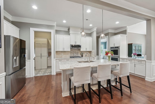 kitchen with stainless steel appliances, a sink, ornamental molding, tasteful backsplash, and white cabinets