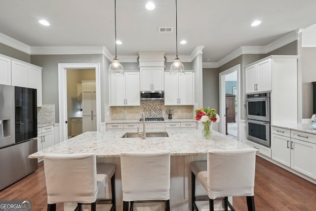 kitchen with stainless steel appliances, a sink, a kitchen bar, backsplash, and ornamental molding