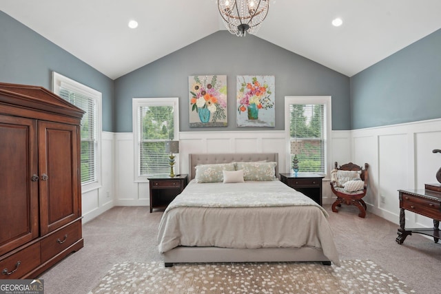 bedroom with light carpet, lofted ceiling, a wainscoted wall, and a decorative wall