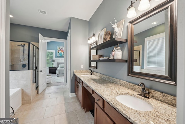 ensuite bathroom with a tile shower, double vanity, tile patterned flooring, and baseboards