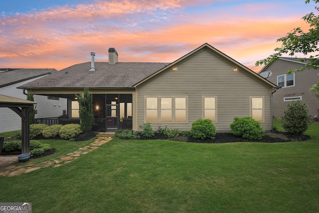 view of front facade with a gazebo, a chimney, a lawn, and a shingled roof