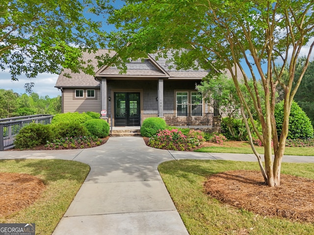 view of front of property with french doors, roof with shingles, and covered porch
