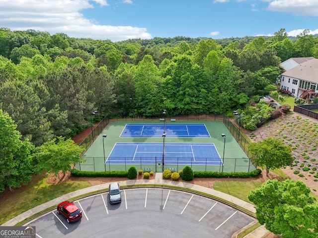 view of tennis court featuring fence and a forest view
