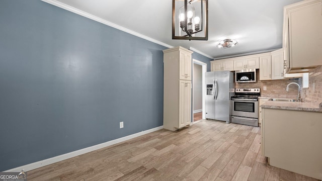 kitchen with appliances with stainless steel finishes, a sink, crown molding, tasteful backsplash, and light wood-type flooring