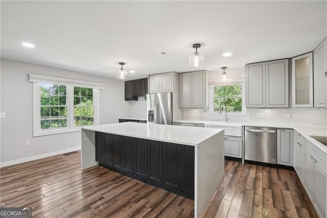 kitchen with stainless steel appliances, dark wood finished floors, a kitchen island, healthy amount of natural light, and recessed lighting