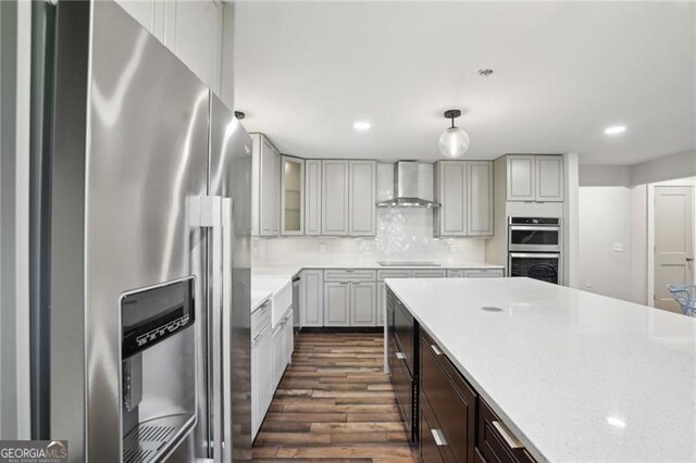 kitchen with stainless steel appliances, wall chimney exhaust hood, dark wood finished floors, recessed lighting, and tasteful backsplash