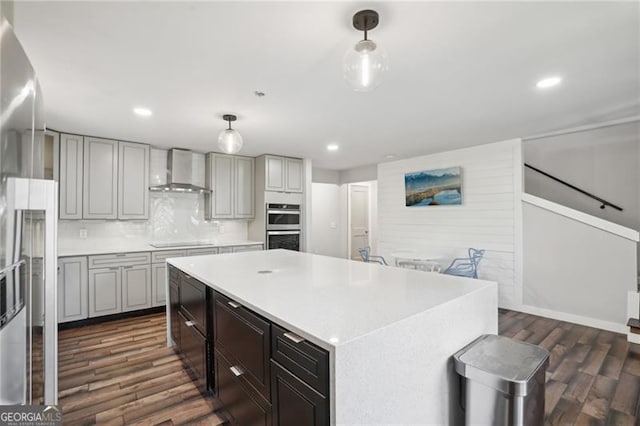 kitchen featuring wall chimney exhaust hood, appliances with stainless steel finishes, dark wood-style floors, light countertops, and recessed lighting
