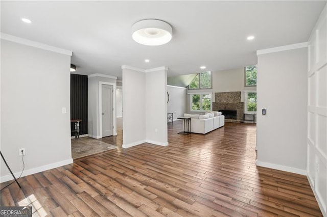 living area featuring a fireplace, crown molding, wood finished floors, baseboards, and recessed lighting