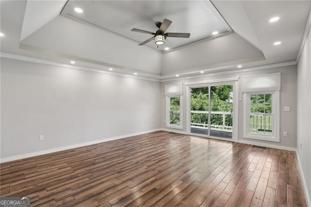 unfurnished room with a raised ceiling, wood finished floors, ceiling fan, ornamental molding, and baseboards