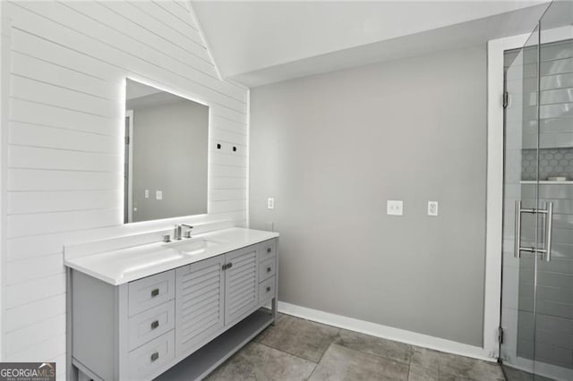 full bath featuring vanity, a stall shower, vaulted ceiling, baseboards, and tile patterned floors