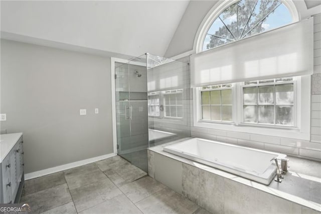 bathroom with a shower stall, vanity, lofted ceiling, a bath, and baseboards
