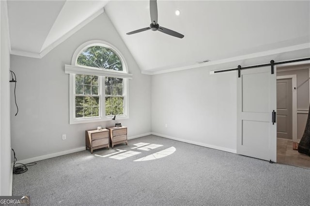 unfurnished bedroom with a barn door, vaulted ceiling, carpet, baseboards, and a ceiling fan