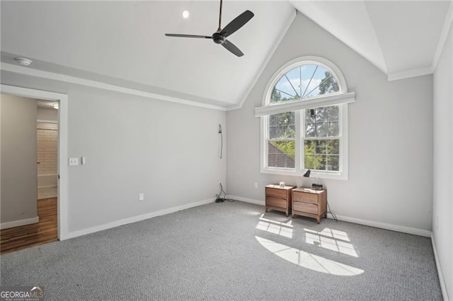carpeted empty room with a ceiling fan, baseboards, and high vaulted ceiling