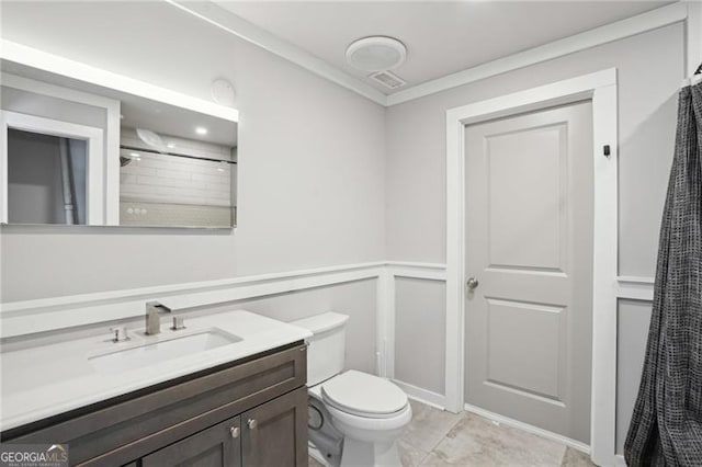 bathroom featuring a decorative wall, toilet, vanity, and a wainscoted wall