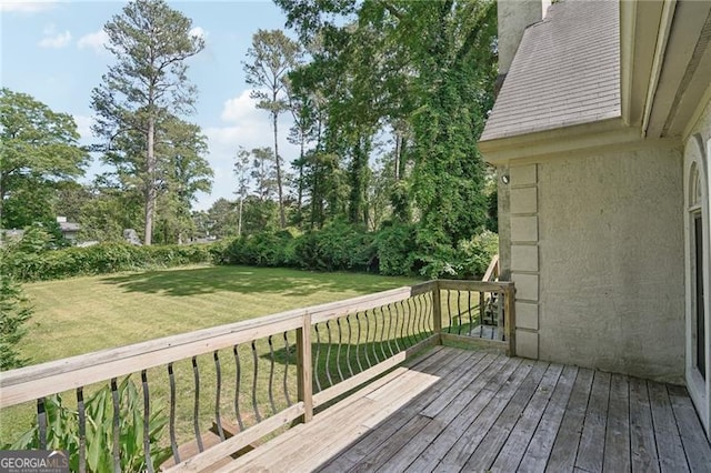 deck with a lawn and view of wooded area