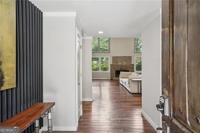 foyer entrance featuring baseboards, dark wood finished floors, a brick fireplace, and recessed lighting