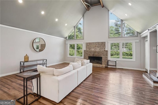 living room featuring high vaulted ceiling, wood finished floors, healthy amount of natural light, a brick fireplace, and recessed lighting