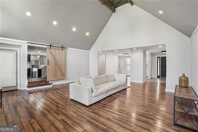 living room with high vaulted ceiling, a barn door, dark wood-style flooring, recessed lighting, and baseboards