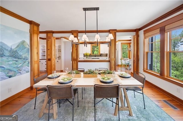 dining room featuring wood finished floors, baseboards, and ornamental molding