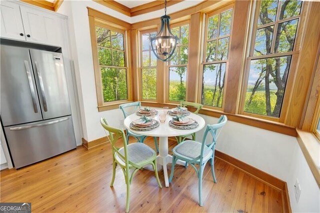 dining room featuring baseboards, light wood finished floors, a chandelier, and plenty of natural light