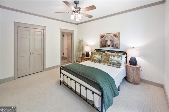 carpeted bedroom featuring baseboards, crown molding, a ceiling fan, and a closet