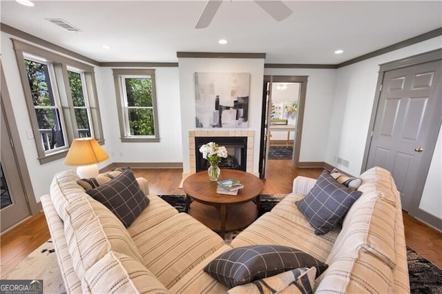living room featuring a ceiling fan, wood finished floors, a tile fireplace, baseboards, and recessed lighting