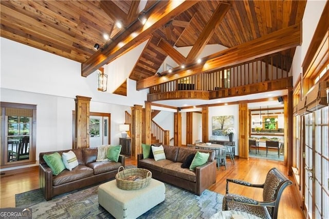 living room featuring beamed ceiling, wood finished floors, wooden ceiling, ornate columns, and stairway