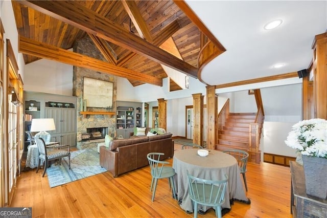 living room featuring stairs, a stone fireplace, wood finished floors, and wood ceiling