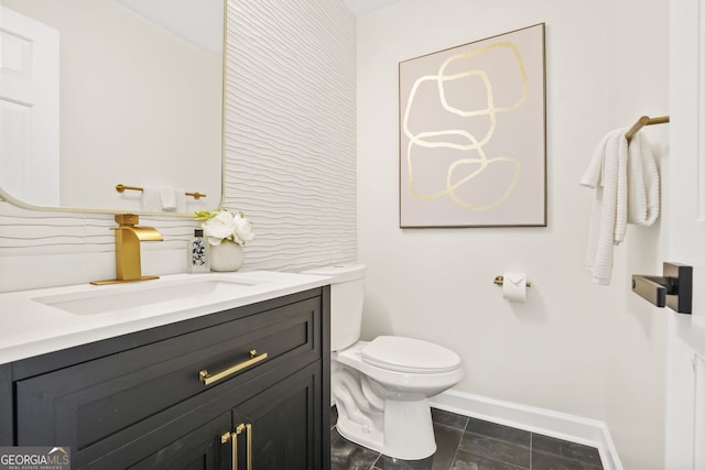 bathroom with baseboards, toilet, and vanity