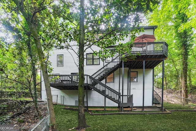rear view of house with stairway, a wooden deck, and a lawn