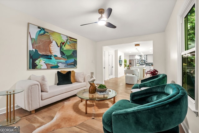 living area featuring wood finished floors, a ceiling fan, and baseboards