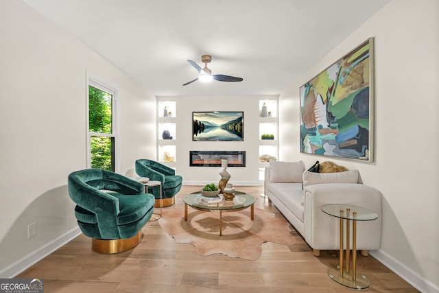 living room with ceiling fan, built in features, wood finished floors, and baseboards