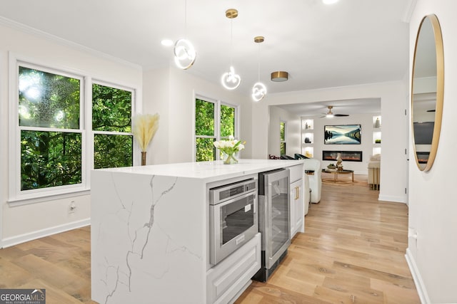 kitchen with beverage cooler, crown molding, white cabinets, and healthy amount of natural light