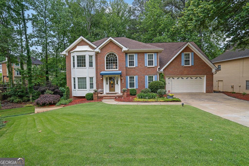 4373 Mikandy Dr NW, Kennesaw, GA 30144 - colonial inspired home featuring brick siding, concrete driveway, and a front yard