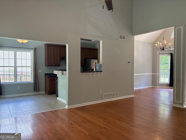2828 Hicks Rd SW, Marietta, GA 30060 - unfurnished living room with high vaulted ceiling, a chandelier, light wood-style flooring, ceiling fan, and baseboards