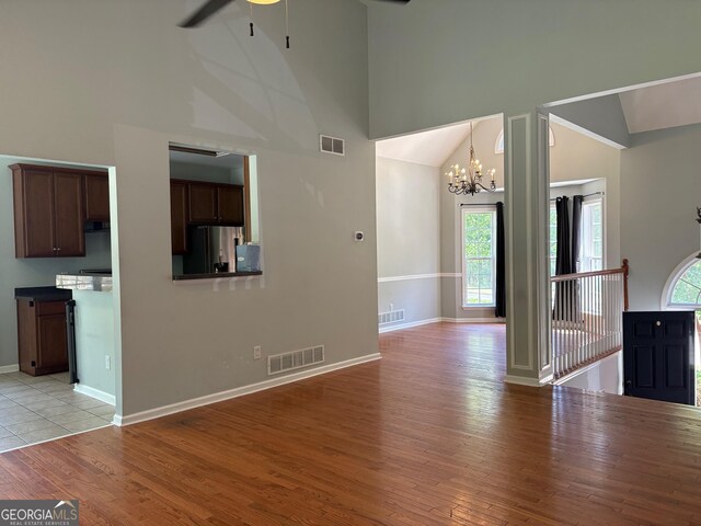 2828 Hicks Rd SW, Marietta, GA 30060 - unfurnished living room with high vaulted ceiling, a ceiling fan, plenty of natural light, a chandelier, and light wood finished floors