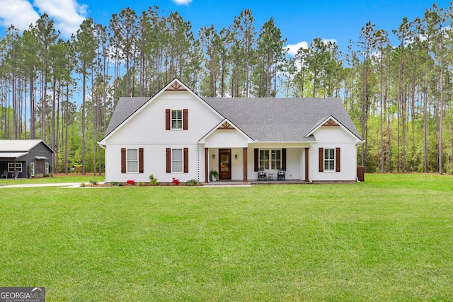 modern inspired farmhouse with covered porch, a front yard, and a shingled roof
