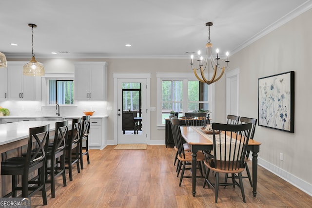dining room with a chandelier, light wood-type flooring, crown molding, baseboards, and recessed lighting